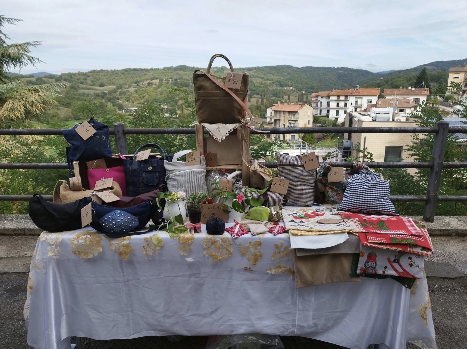 Il banchetto di Assunta con tante borse fatte a mano, davanti alle colline